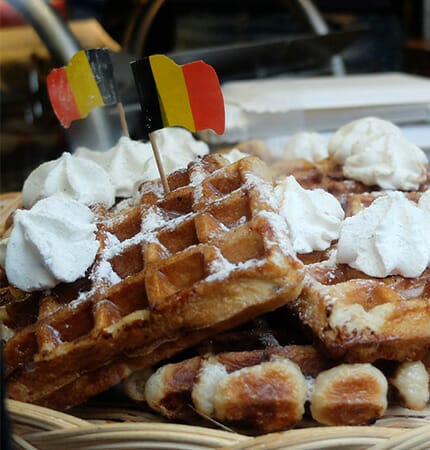 Belgian waffles with whipped cream and belgian flag on plate in Brussels restaurant