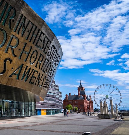 popular Cardiff tourist venues in Wales with cloudy blue sky and ferris wheel in background