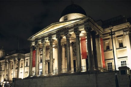 front side of national portrait gallery of london at night with lights on facade