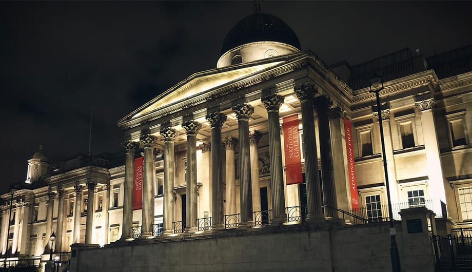 front side of national portrait gallery of london at night with lights on facade