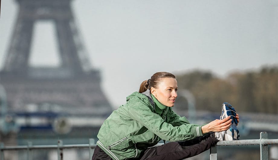 Female Runner stretching before the Paris Marathon race with Eiffel Tower behind her