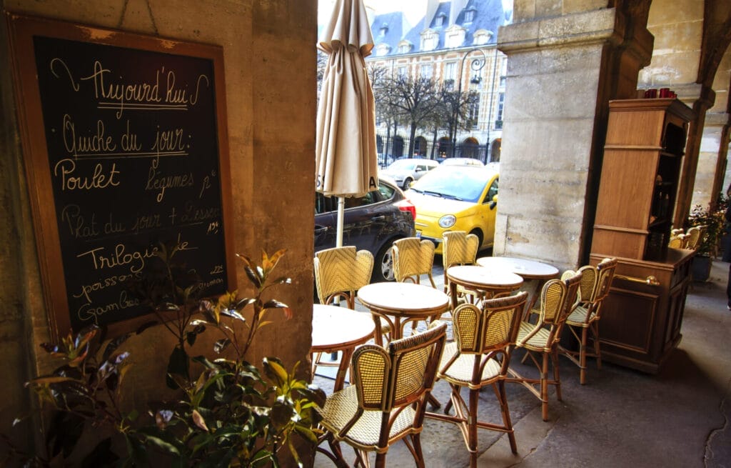 Paris cafe under arches with it's aligned tables and menu board on the wall.